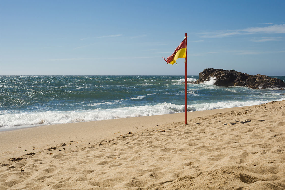 Červeno-žlutá vlajka na pláži v Portu, Portugalsko